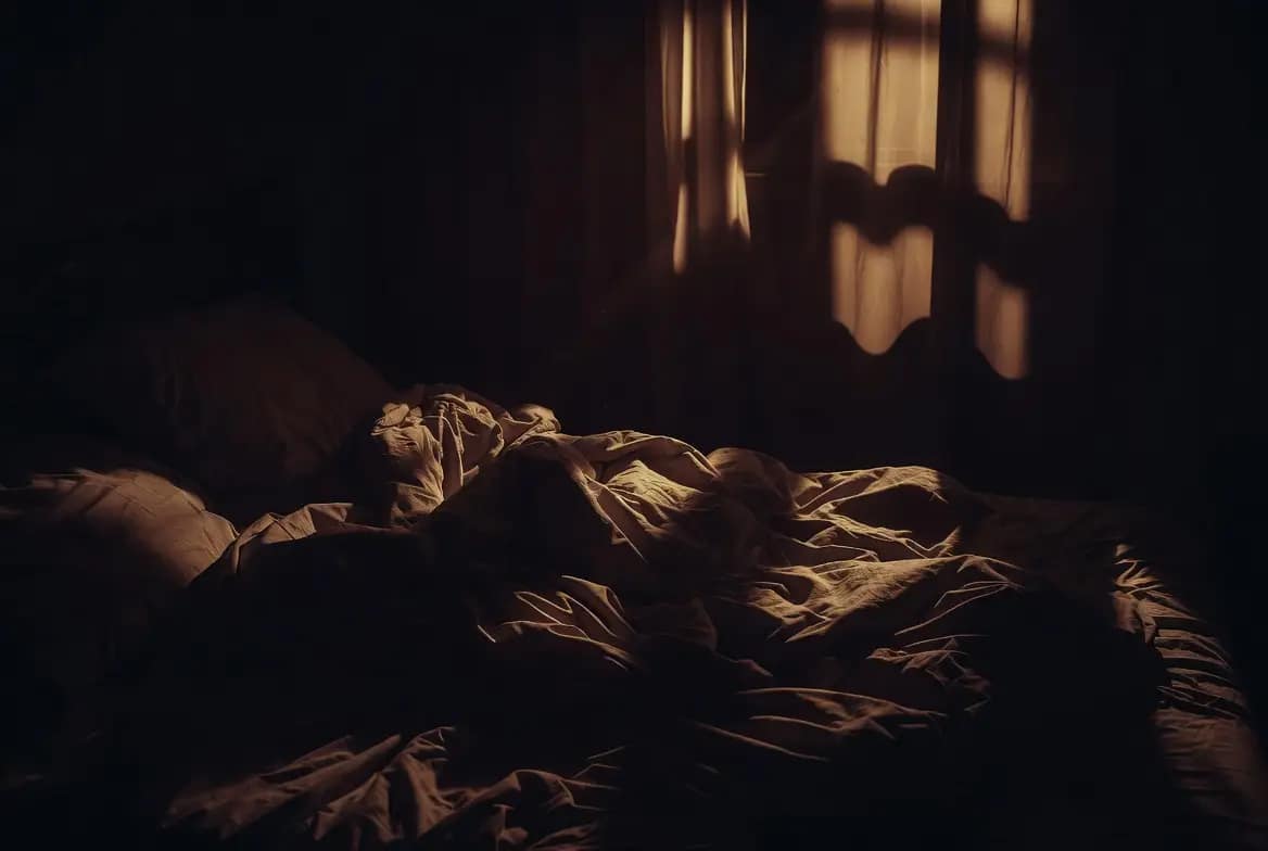 Chambre sombre et lit défait évoquant une nuit hantée par des cauchemars récurrents d'origine spirituelle