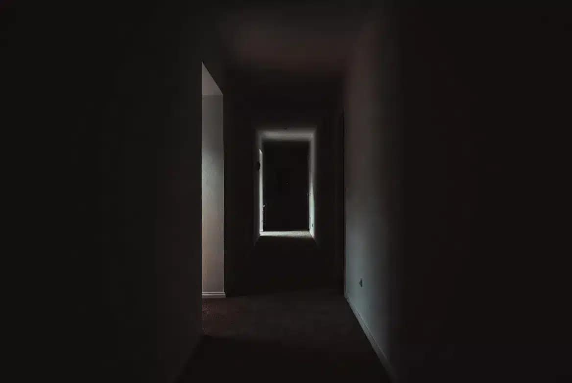 Djinn dans la maison : présence invisible ressentie dans un couloir sombre la nuit, sensation d'être observé chez soi