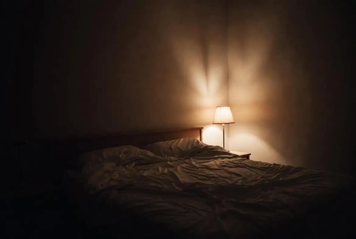Chambre faiblement éclairée la nuit, moment où apparaissent les griffures et marques inexpliquées sur le corps pendant le sommeil