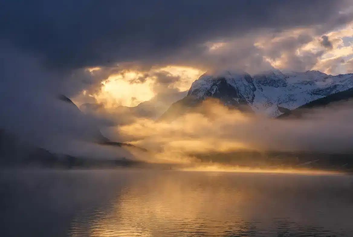 Paysage suisse mystique à l'aube avec montagnes des Alpes et lac, évoquant l'identité géographique et spirituelle de Well Therapy basé à Renens, canton de Vaud